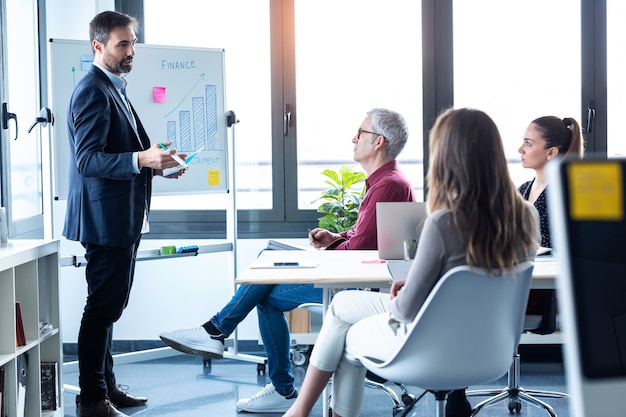 Shot of handsome businessman explaining a project to his colleagues on coworking place.