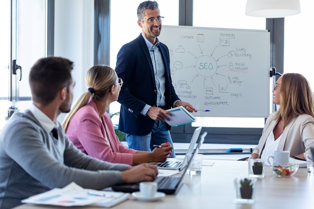 Scatto di un bell'uomo d'affari che spiega un progetto ai suoi colleghi in un luogo di coworking.