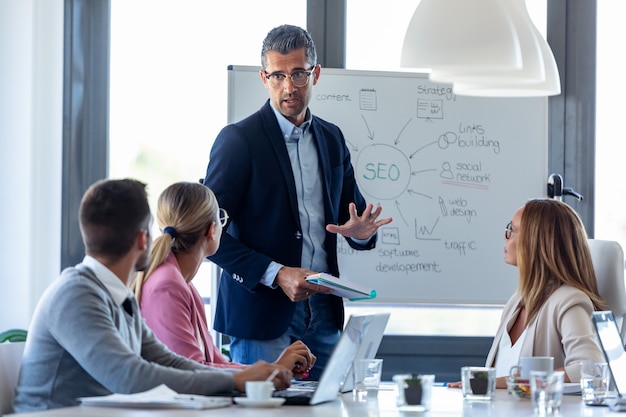 Photo shot of handsome businessman explaining a project to his colleagues on coworking place.