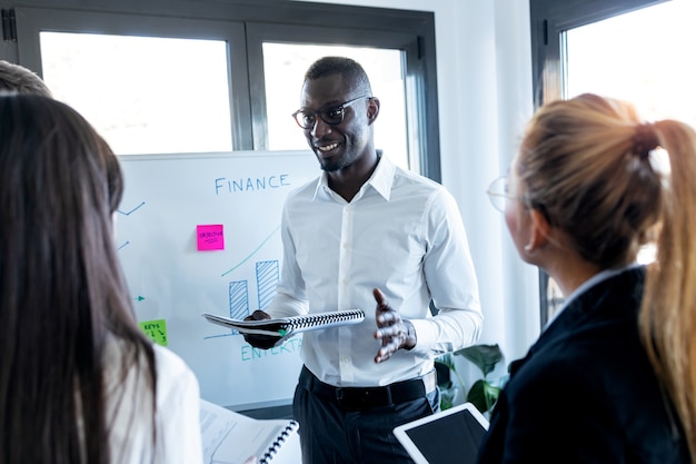 Shot of handsome young businessman explaining a project to his colleagues on coworking place.