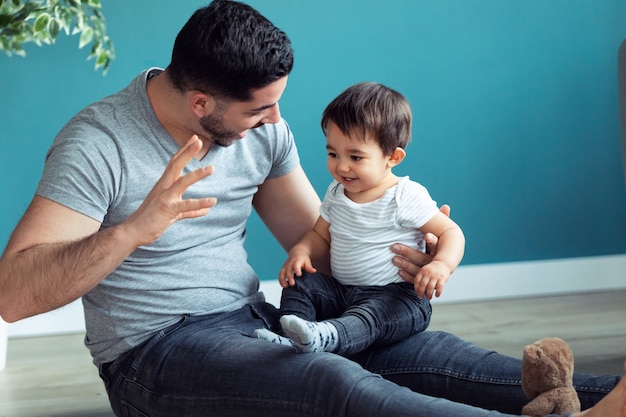 Shot of handsome young father with his baby playing together and having fun at home.