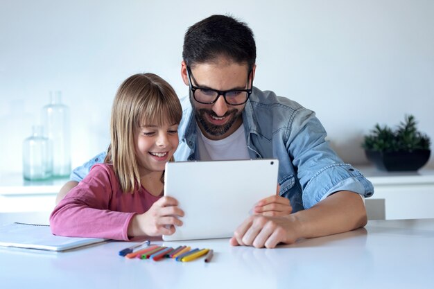 Shot of handsome young father with his little daughter using digital tablet at home.