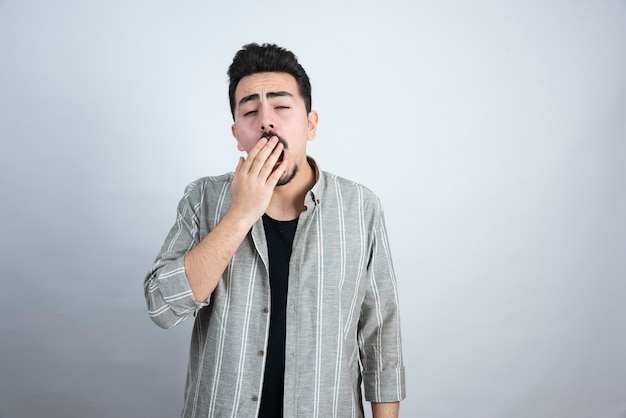 Colpo di bel giovane con la barba in piedi e sensazione di sonnolenza.