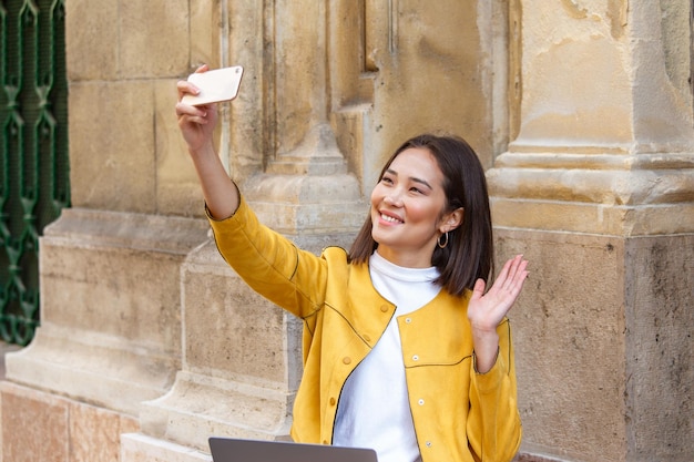 Inquadratura di una giovane donna asiatica felice che si fa selfie con il cellulare smartphone cellulare nelle mani di una giovane donna asiatica attraente che scatta foto o selfie per le strade