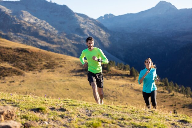 Shot of healthy young couple running on mountain trail in the morning.