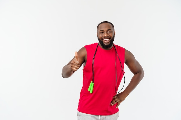 Shot of masculine man skipping rope, Muscular young man exercising with jumping rope on grey