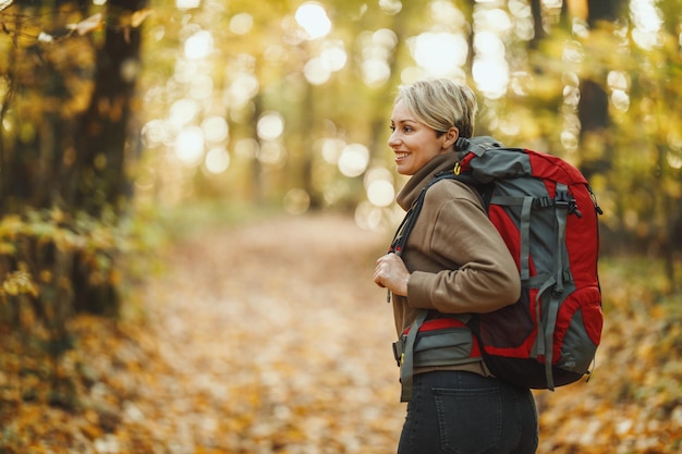 Inquadratura di una donna matura che cammina attraverso la foresta in autunno.