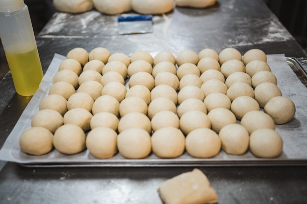 Shot of metal tray full of balls of bread dough in a row in a bakery