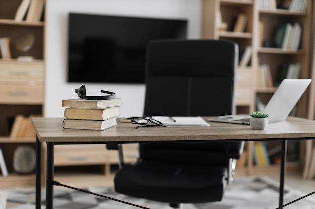 Shot of modern workplace office with laptop books papers eyeglasses headset on wood table