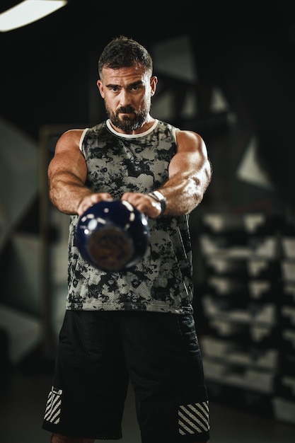 Shot of a muscular guy in sportswear doing russian kettlеbell swing exercises  at the gym.