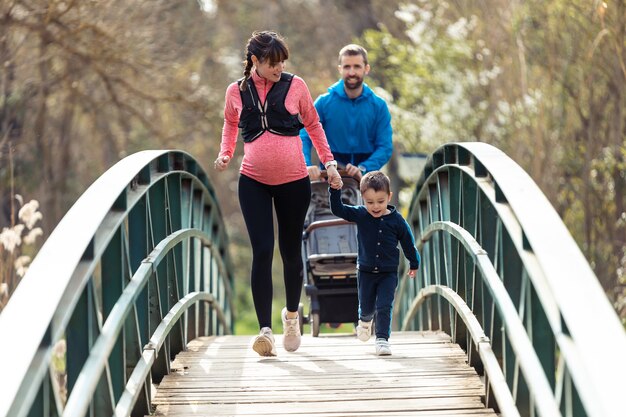 Shot of pregnant young woman with her little son running while enjoying the time together outdoor.