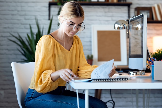 Shot of pretty freelance business woman seller reading some information while working with computer in her startup small business.