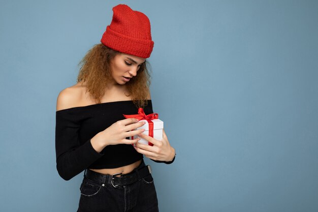 Shot of pretty positive surprised young dark blonde curly woman isolated over blue background wall