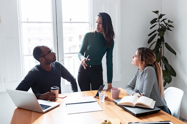 Shot of pretty young entrepreneur woman explaining a project to his colleagues on coworking place.