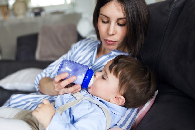 Scatto di una bella giovane madre che allatta il suo bambino con il latte sul biberon nel soggiorno di casa.