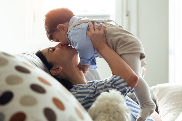 집에 있는 거실에서 아기가 놀고 사랑하는 예쁜 젊은 어머니의 사진.