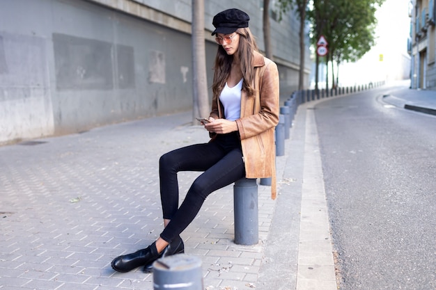 Shot of pretty young woman using her mobile phone while sitting in the street.