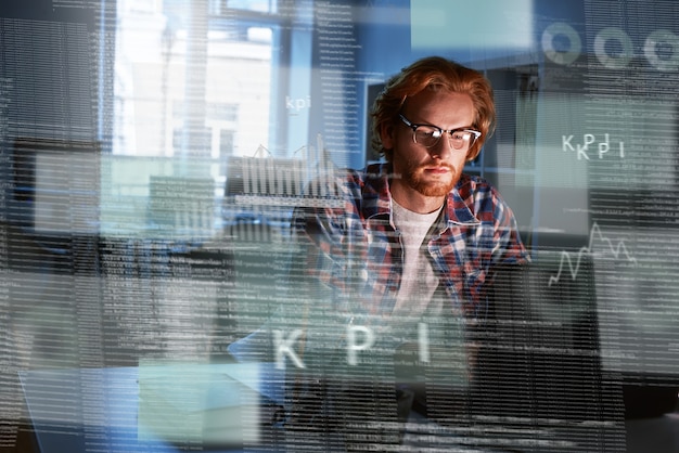 Photo shot of a red haired computer programmer who works on new code. he looks concentrated and thougtful. artifitial intelligence developer