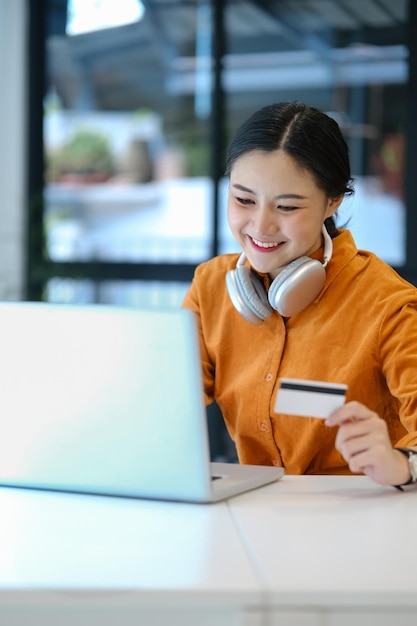 Shot of Shopping online concept Office woman holding credit card and using laptop computer