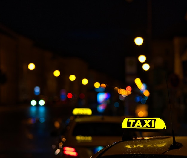 Photo shot of the taxi sign on the car and lights of the street during the nighttime