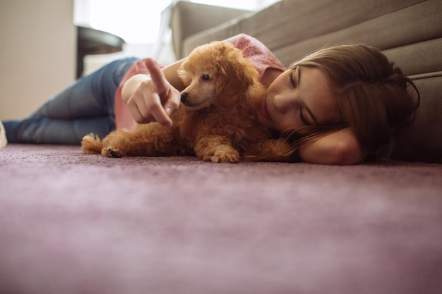 子犬と一緒に床に横たわっているティーンエイジャーのショット