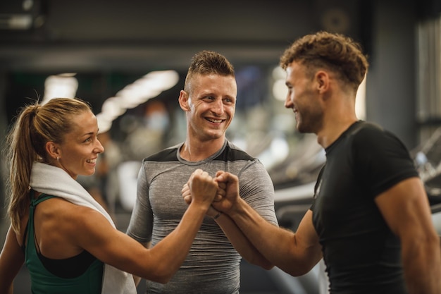 Shot of three young people joining their fists together in\
solidarity at a gym.