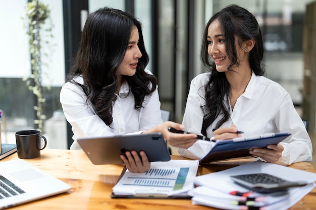 Снимок двух азиатских деловых женщин, работающих вместе на цифровом планшете Креативные женщины-руководители встречаются и обсуждают сидя в офисе