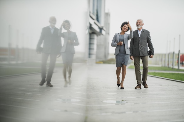 Shot of two successful multi-ethnic business people talking while walking during a coffee break in front of the office building.