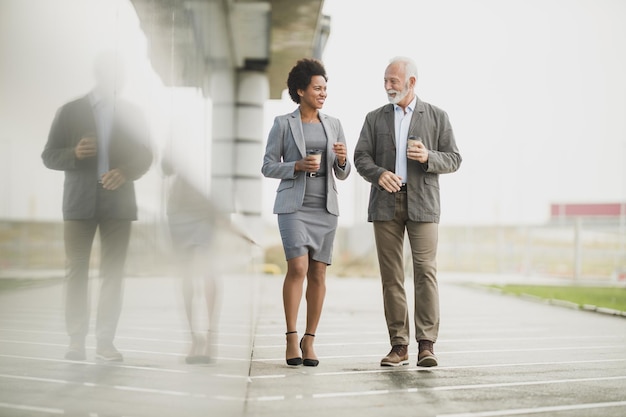 Shot of two successful multi-ethnic business people talking while walking during a coffee break outdoors.