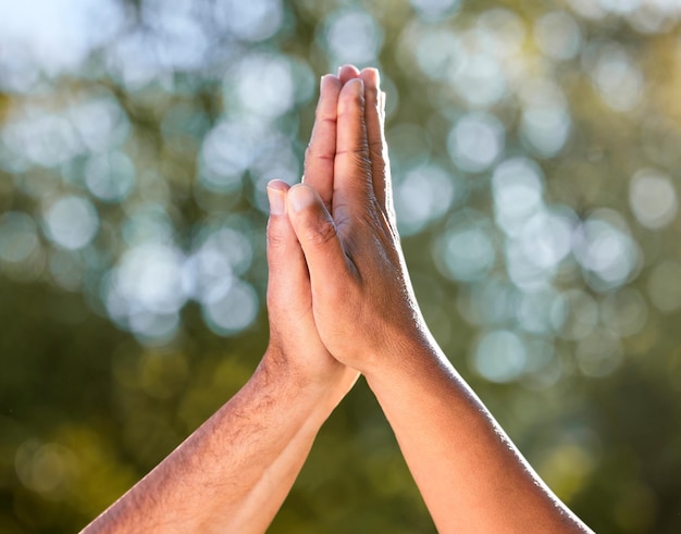 Photo shot of two unrecognisable men giving each other a high five outdoors