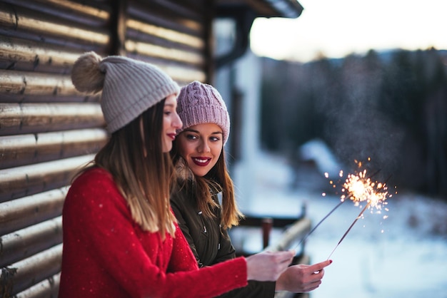 Shot of two women enjoying holding sparkling sticks in the winter.