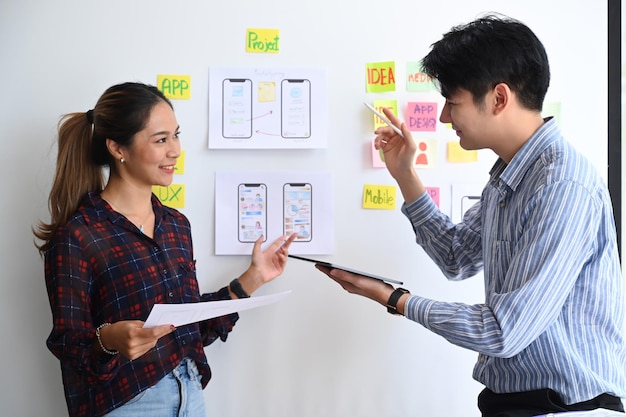 Shot of ux developer and ui designer brainstorming and discussing about mobile app interface wireframe design on white board