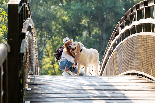 Shot van aantrekkelijke jonge amateur foto vrouw kuste haar hond oversteken van een brug in het park.