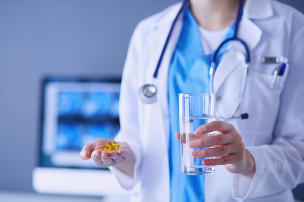 shot van de handen van de dokter met pillen en glas water in de kliniek.