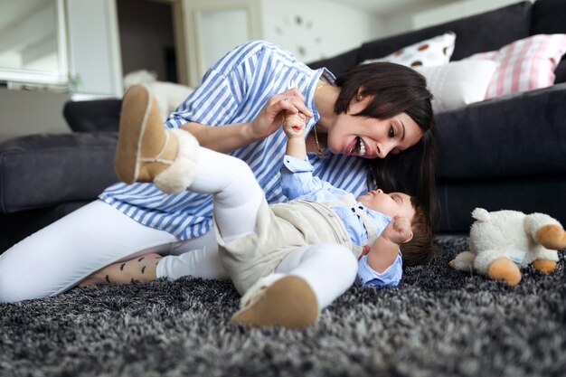 Shot van een gelukkige jonge moeder met haar baby die thuis op de vloer van de woonkamer speelt.