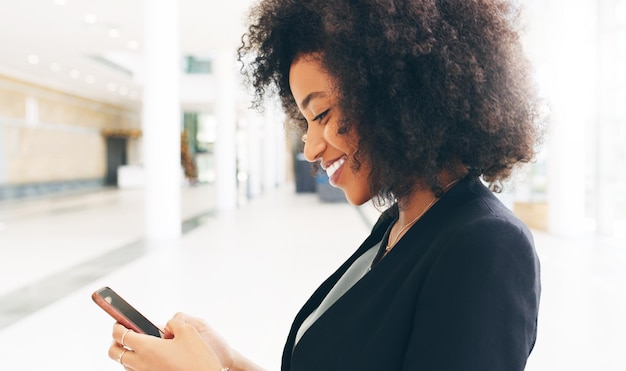 Shot van een gelukkige jonge zakenvrouw die een smartphone gebruikt in een modern kantoor