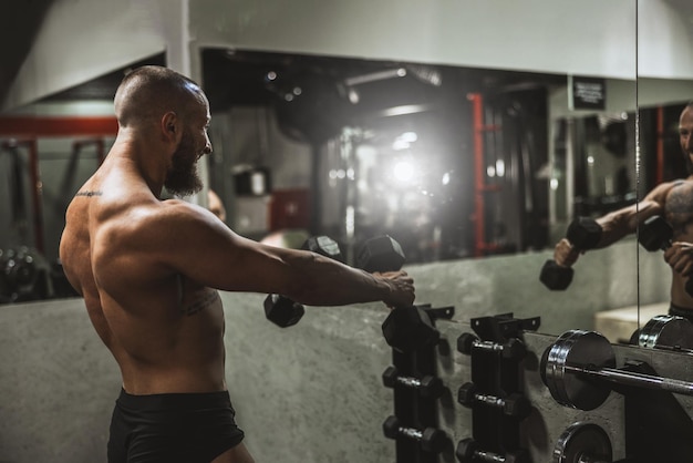 Shot van een gespierde bodybuilder die hard traint met halter in de sportschool.