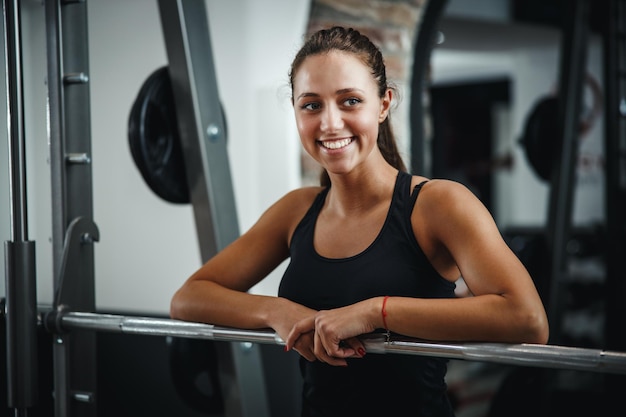 Shot van een gespierde jonge vrouw in sportkleding die zich voordeed tijdens het trainen in de sportschool. Ze bereidt halter voor de start van de volgende reeks oefeningen.