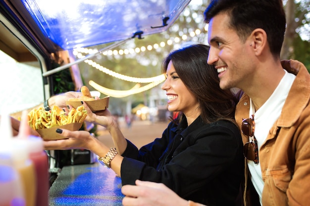 Shot van een groep aantrekkelijke jonge vrienden die verschillende soorten fastfood kiezen en kopen op de eetmarkt op straat.