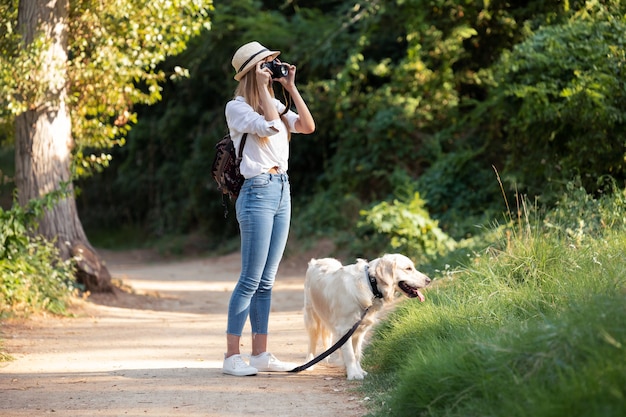 Shot van een jonge amateurfotograaf die een foto van het landschap maakt terwijl ze met haar hond in het park wandelt.