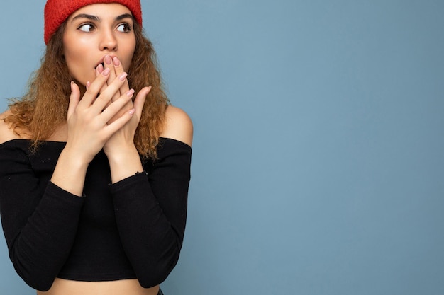 Foto shot van een jonge, emotioneel geschokte verbaasde aardige, innemende brunette vrouw met golvend haar en oprechte emoties