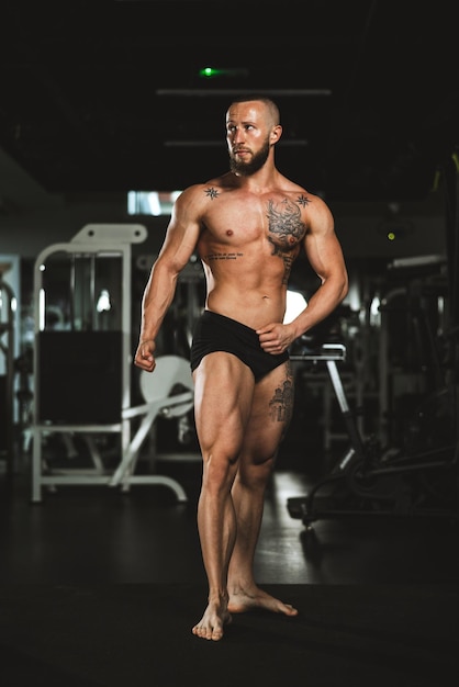 Shot van een jonge gespierde bodybuilder die zijn perfecte spieren laat zien terwijl hij poseert na het sporten in de sportschool.