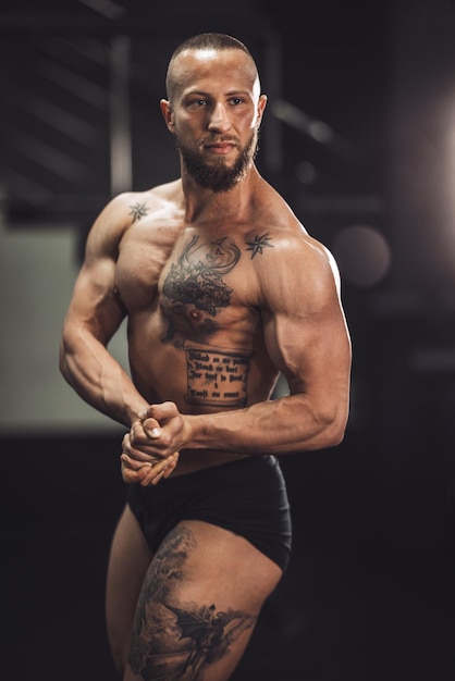 Shot van een jonge gespierde bodybuilder die zijn perfecte spieren laat zien terwijl hij poseert na het sporten in de sportschool.