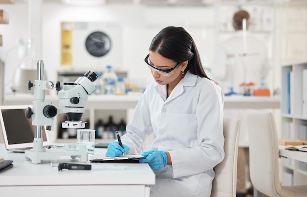 Shot van een jonge wetenschapper die aantekeningen maakt terwijl hij in een laboratorium werkt