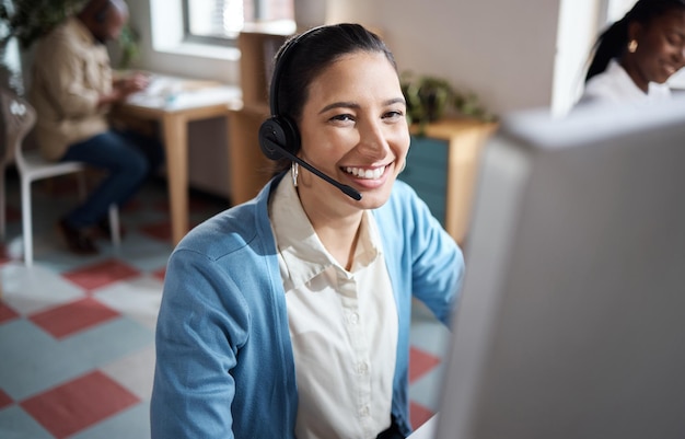 Shot van een jonge zakenman die een headset en computer gebruikt in een modern kantoor