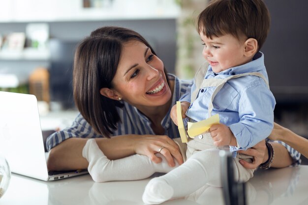 Shot van een mooie jonge moeder met haar baby die thuis met een notitieboekje speelt.