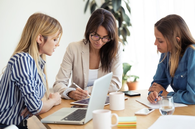 Shot van een mooie jonge zakenvrouw die de voortgang van het werk op een digitale tablet laat zien aan collega's op kantoor.