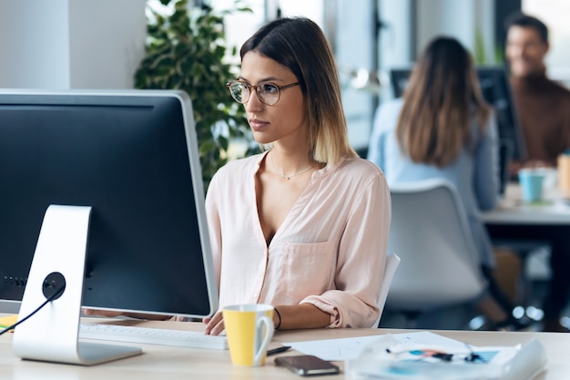 Shot van een mooie jonge zakenvrouw die met de computer werkt terwijl ze aan een bureau zit in een modern opstartkantoor.