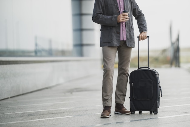 Shot van een onherkenbare senior zakenman die met zijn bagage buiten de luchthaven loopt.