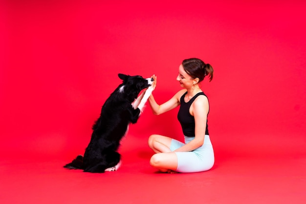 Shot van een sportvrouw in beenkappen met een border collie-hond geïsoleerd op gele en rode achtergrond